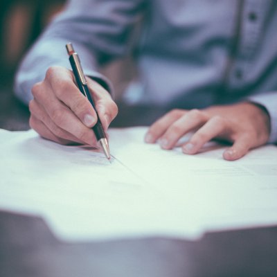 a person filling out a form with a pen